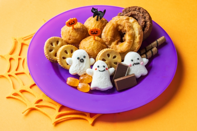 クッキーやキャンディなどハロウィンお菓子がのった紫色の皿