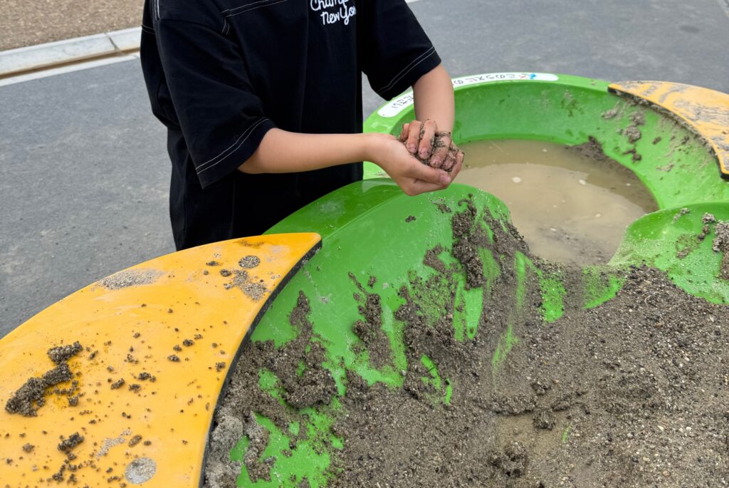 テーブル砂場で泥団子を作っている女の子の手元